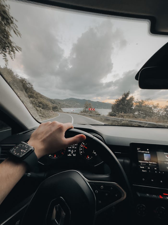 A person drives on a winding mountain road with a stunning view, focusing on the road ahead.